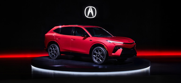 Vista frontal de 7/8 de un Acura Hybrid 2026 en un escenario de estudio oscuro con detalles de iluminación roja.