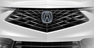 Se muestra la Acura ADX 2026 en Platinum White Pearl con el emblema frontal iluminado accesorio.