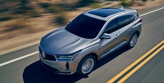 Imagen de la Acura RDX 2022 en Lunar Silver Metallic manejando con sus imponentes líneas Imagen de la Acura RDX 2022 en Lunar Silver Metallic manejando con sus imponentes líneas