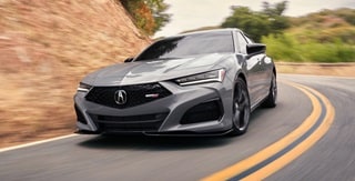 Vista frontal de 3/4 del Acura TLX 2025 con Paquete Type S en Urban Gray Pearl en la carretera. Vista frontal de 3/4 del Acura TLX 2025 con Paquete Type S en Urban Gray Pearl en la carretera.